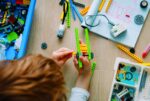 A child builds on his LEGO creation at a desk